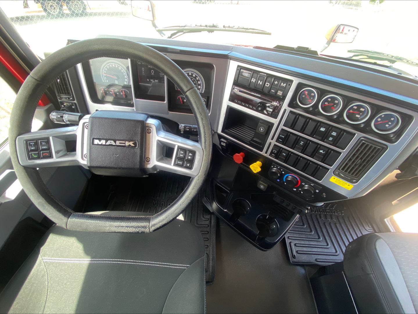 Mack ANTHEM cabin interior showing steering wheel, dashboard with gauges, control switches, and center console.