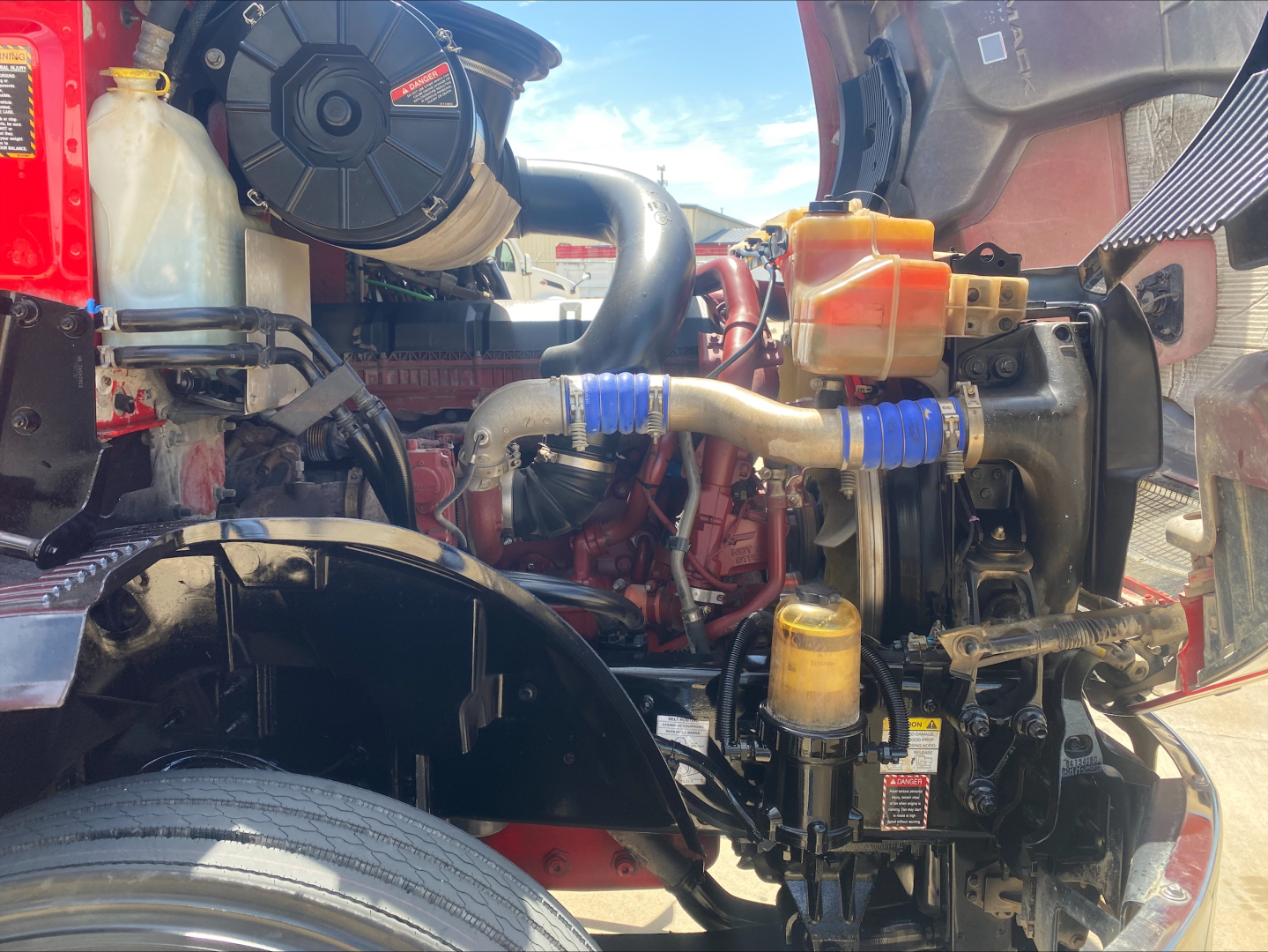 Truck engine bay of a 2021 Mack ANTHEM showing coolant reservoir, hoses, and engine components.