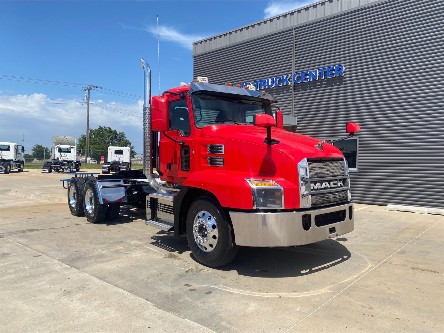 Mack ANTHEM truck in red, front-left view at dealership lot showing cab and chassis with chrome bumper and grille.