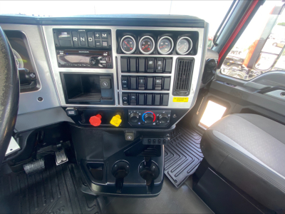 Truck dashboard and center console of a 2021 Mack Anthem showing gear selector, multiple gauges, switches, and pedals.