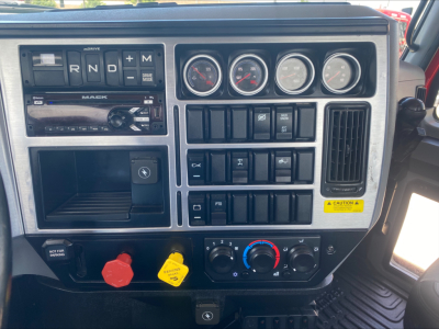 Dashboard view of a 2021 Mack Anthem truck showing R,N,D, and M gear selector, four gauge cluster, control switches, and climate controls.
