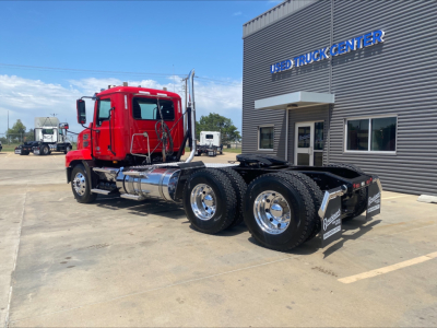 2021 Mack Anthem   red daycab truck with dual rear axles and chrome fuel tanks parked outside a used truck center.