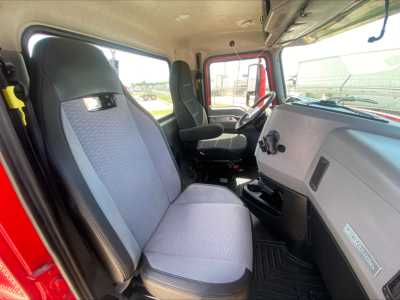 Interior driver and passenger seats of a 2021 Mack Anthem Daycab truck cab, light gray and blue seats, dashboard with steering wheel and controls, view through windshield.