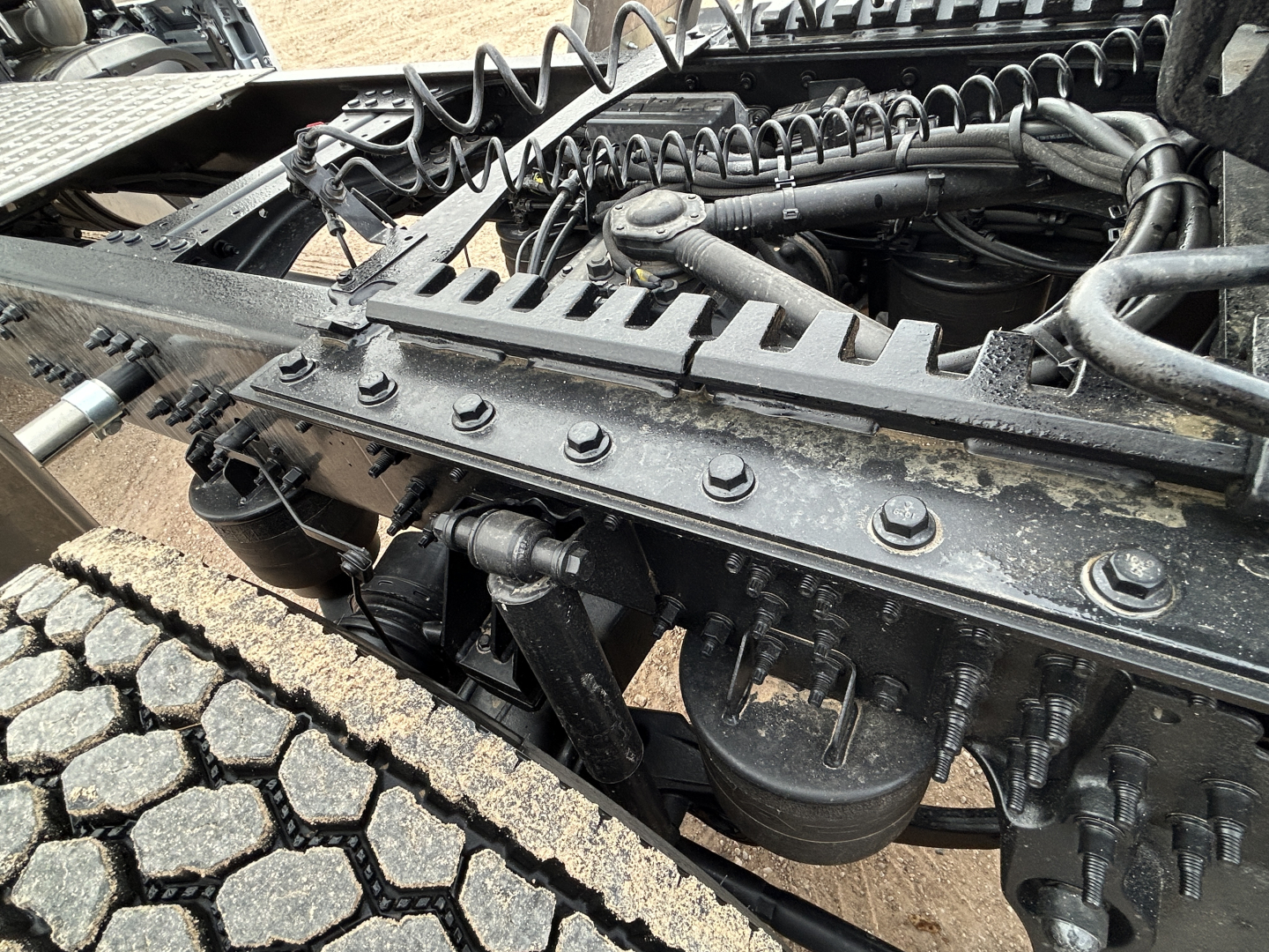 Truck chassis frame with suspension components, air lines, and engine bay visible under cab of a Mack PR64T44.