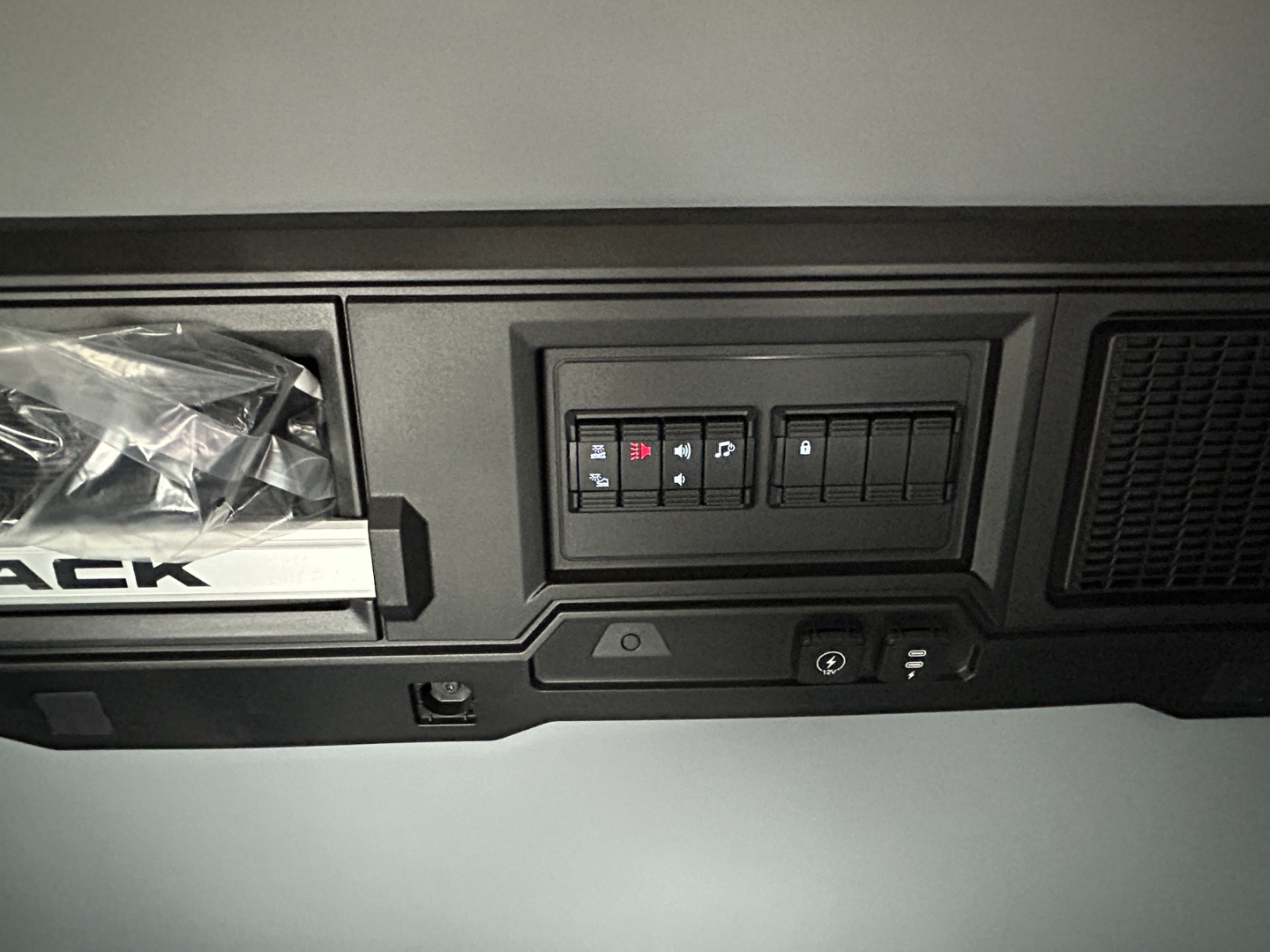 Dashboard area showing switches and controls in a Mack PR64T44 cab interior with storage pocket and vents.
