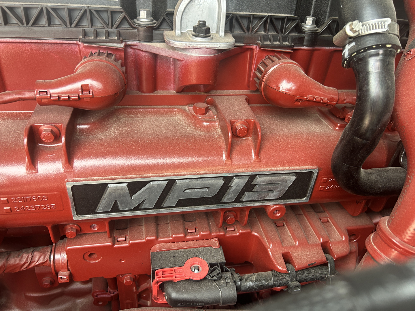 Mack engine bay showing PR 6.0L? engine with MD3 badge and red components, fuel lines, and hoses visible.
