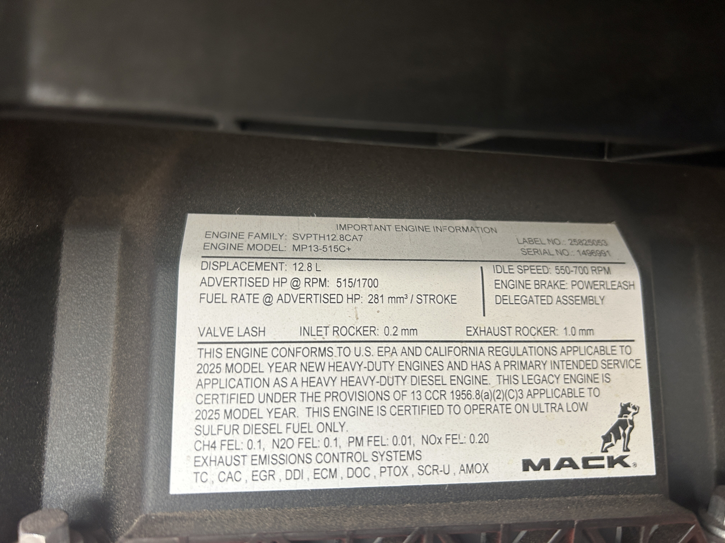 Label on engine information panel with engine family, EPA compliance, displacement 12.8 L, fuel rate, exhaust rocker, valve lash 0.2 mm, exhaust 1.0 mm, and other technical specs for a Mack engine.
