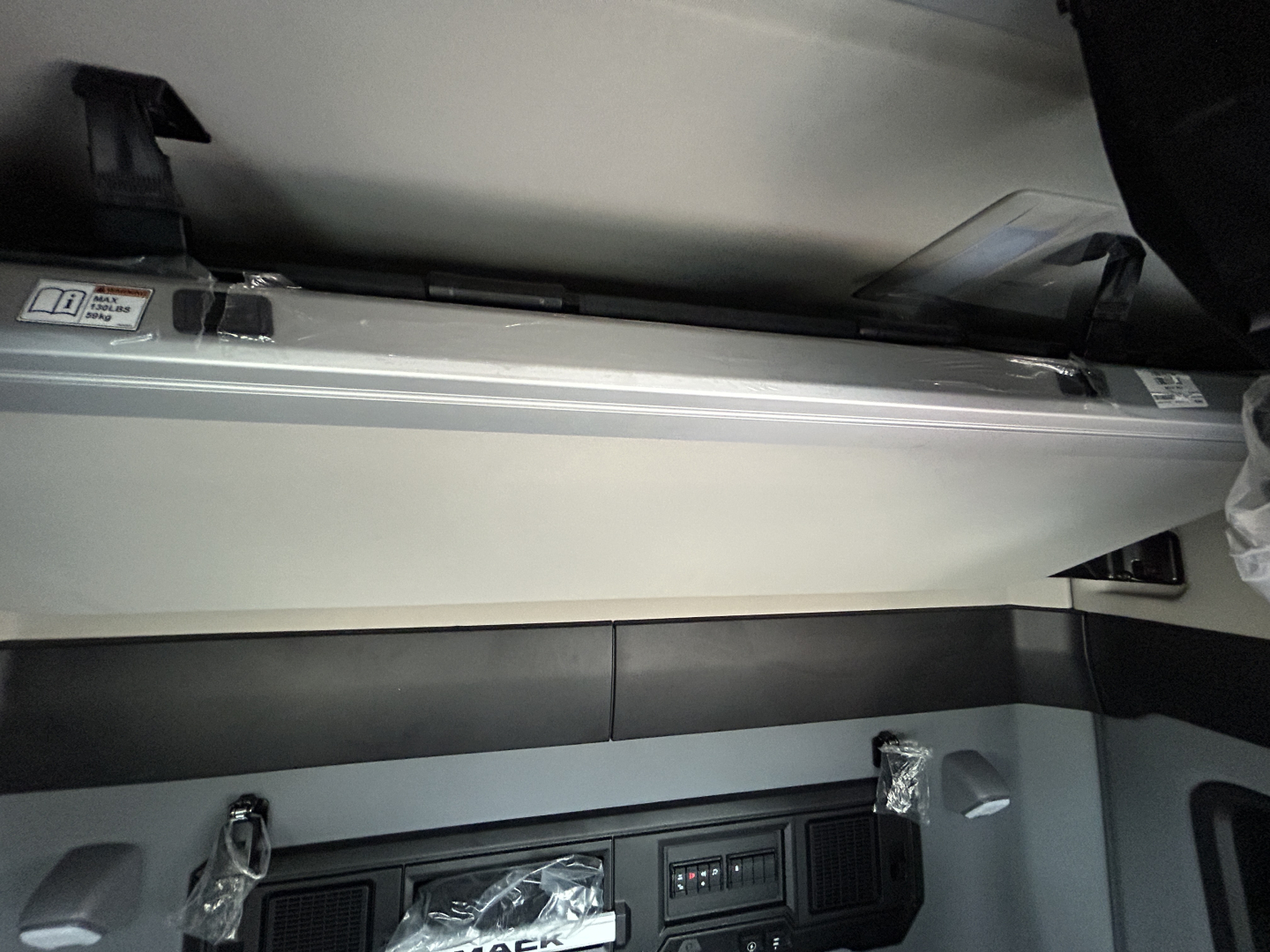 Interior view of a Mack PR64T44 truck cabin showing a storage shelf and control panel area.