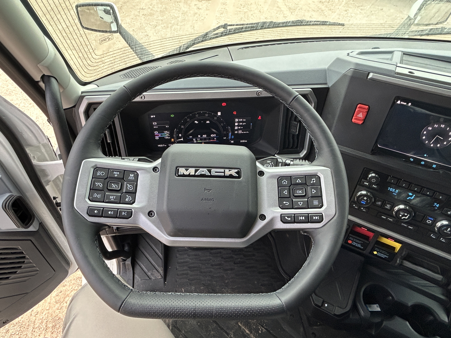 Mack PR64T44 truck interior steering wheel with control buttons and dashboard displays visible.