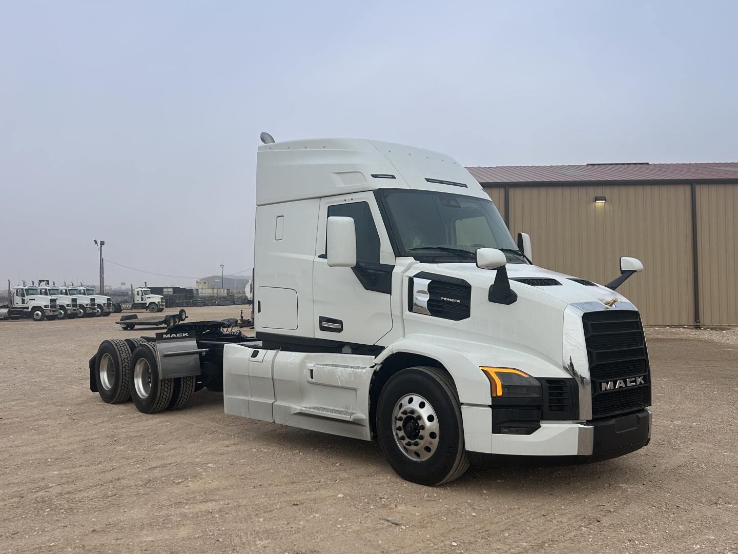 Mack PR64T44 conventional sleeper tractor front-left view showing cab, grill, and dual rear axles with white paint and black accents.