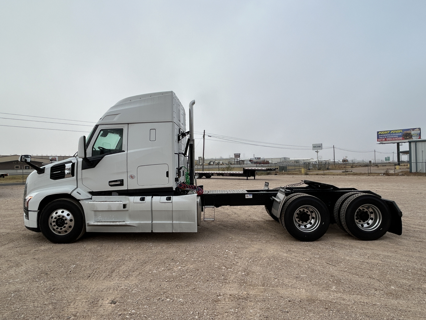 Truck chassis with cab in sleepered configuration, side view showing Mack PR64T44 chassis with dual rear axles and bare flatbed frame.