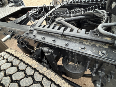 Truck chassis frame with suspension components, air lines, and engine bay visible under cab of a Mack PR64T44.