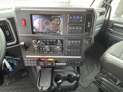 Mack PR64T44 truck interior dashboard view showing touchscreen display, control panels, climate controls, and cup holders.