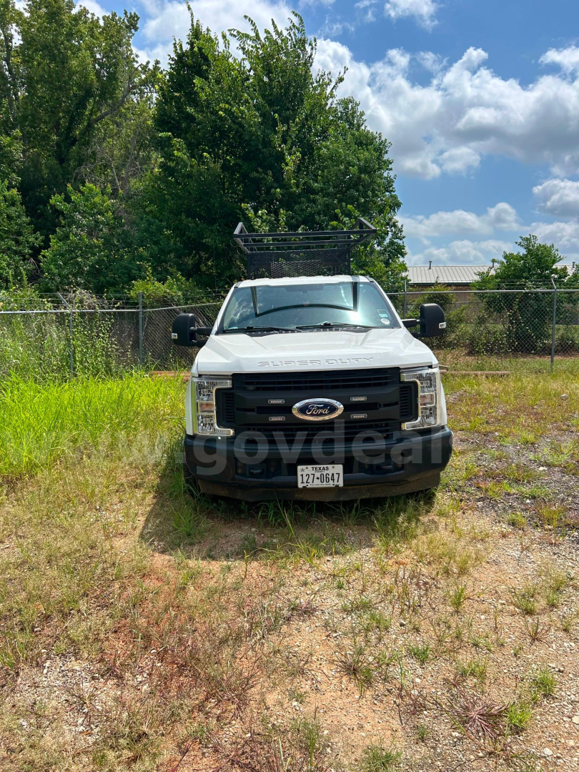 Ford F-350 service/utility truck front view with black grille, Ford emblem, ladder rack on roof, Texas license plate, and side mirrors.