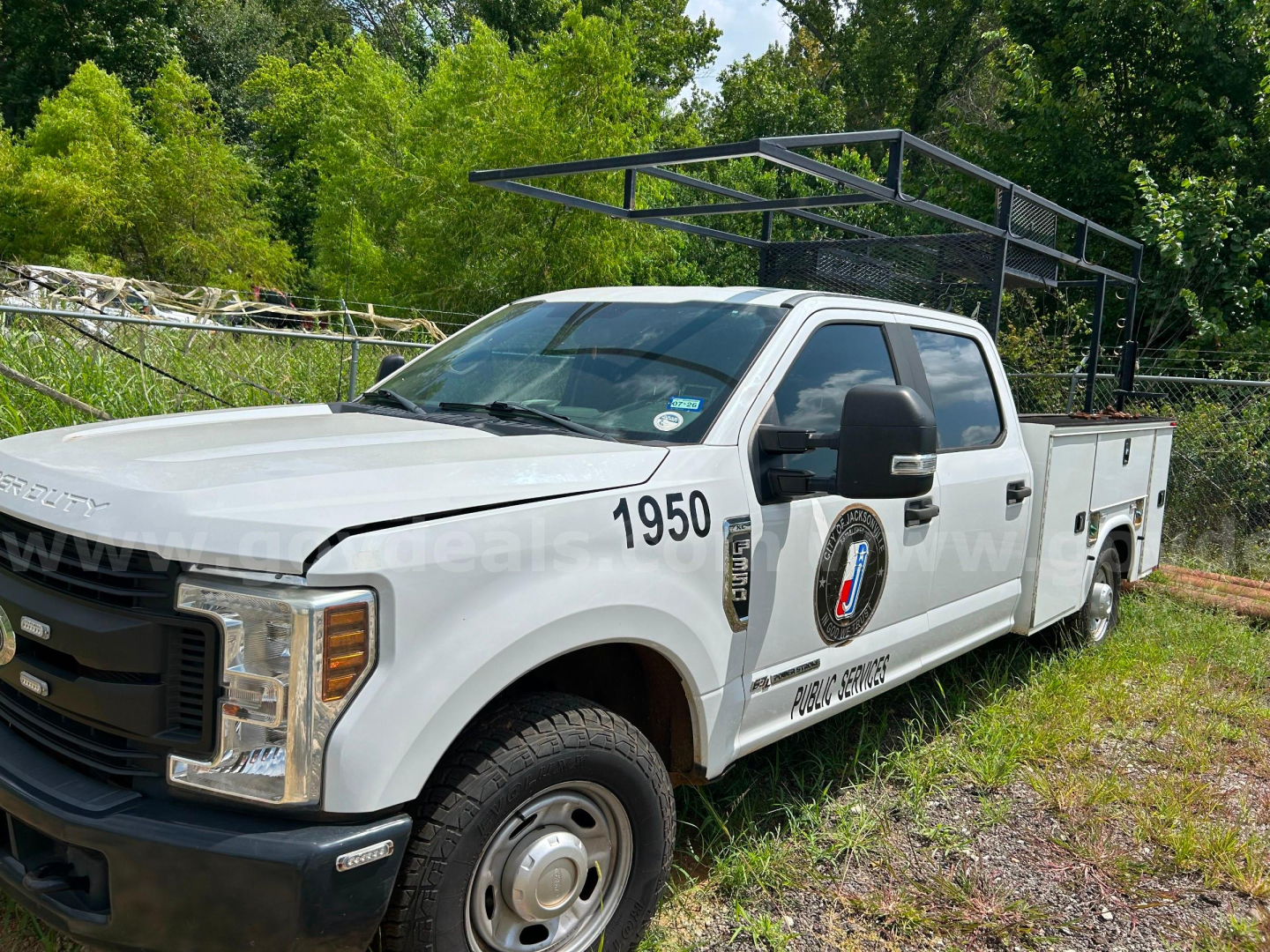 Ford F-350 service truck in-profile showing white crew cab with service body and ladder rack.