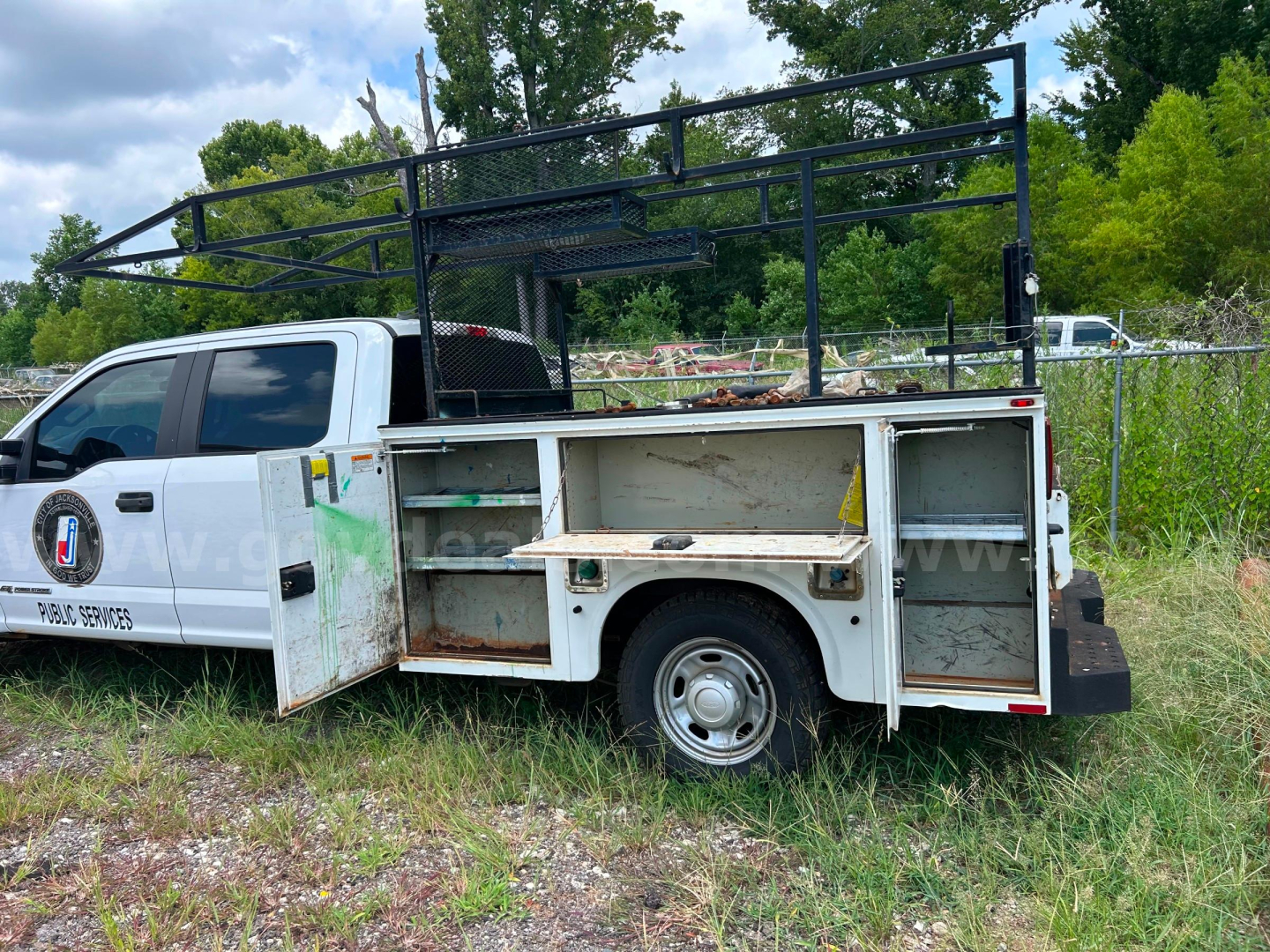 Service/utility truck body with open side compartments, Ford F-350 utility bed, metal ladder rack, white cab, black trim, exposed storage bins.