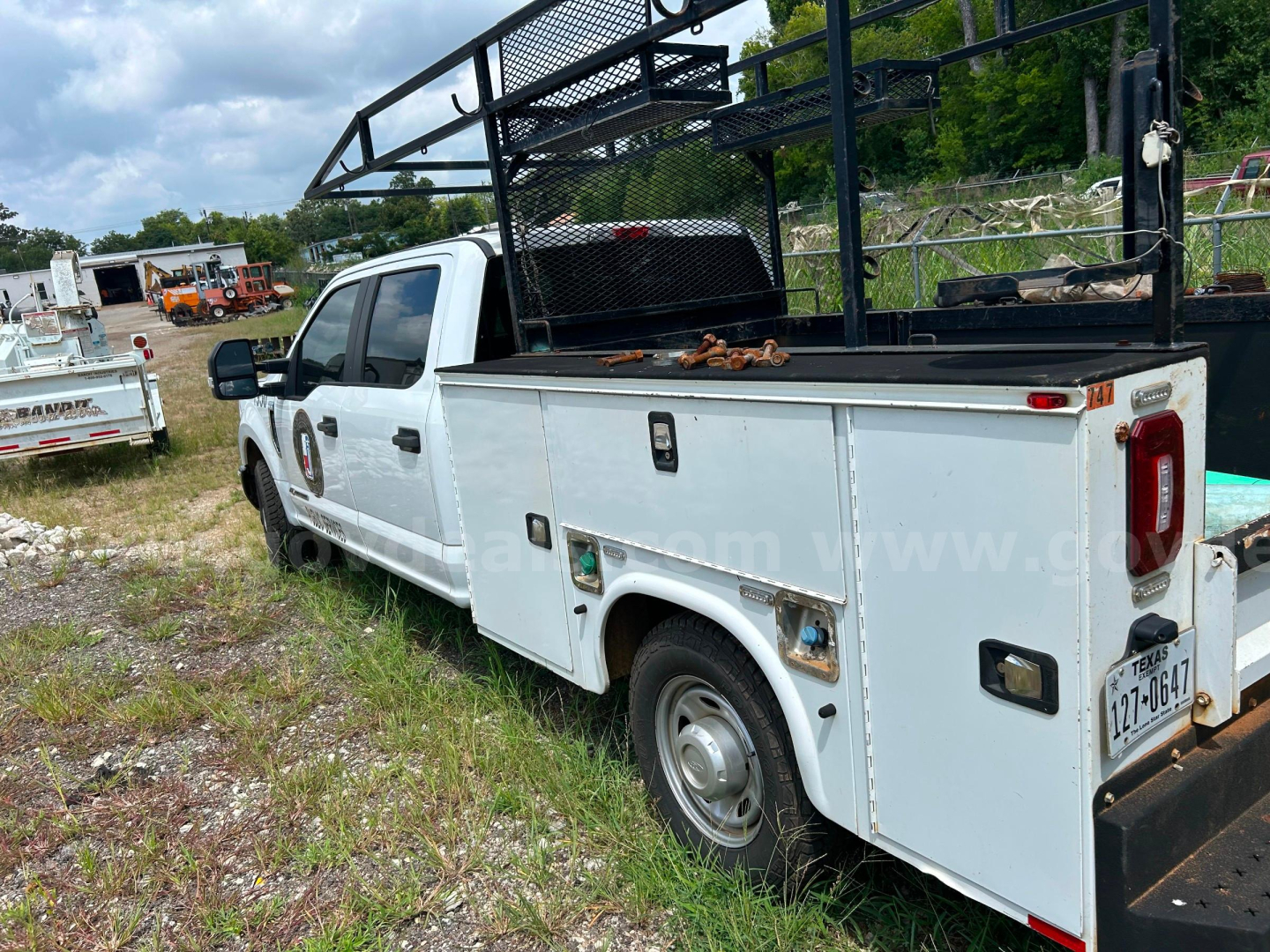 Ford F-350 service/utility truck with utility body and side compartments, rear ISO taillight, mounted rack in bed, white color, used condition.