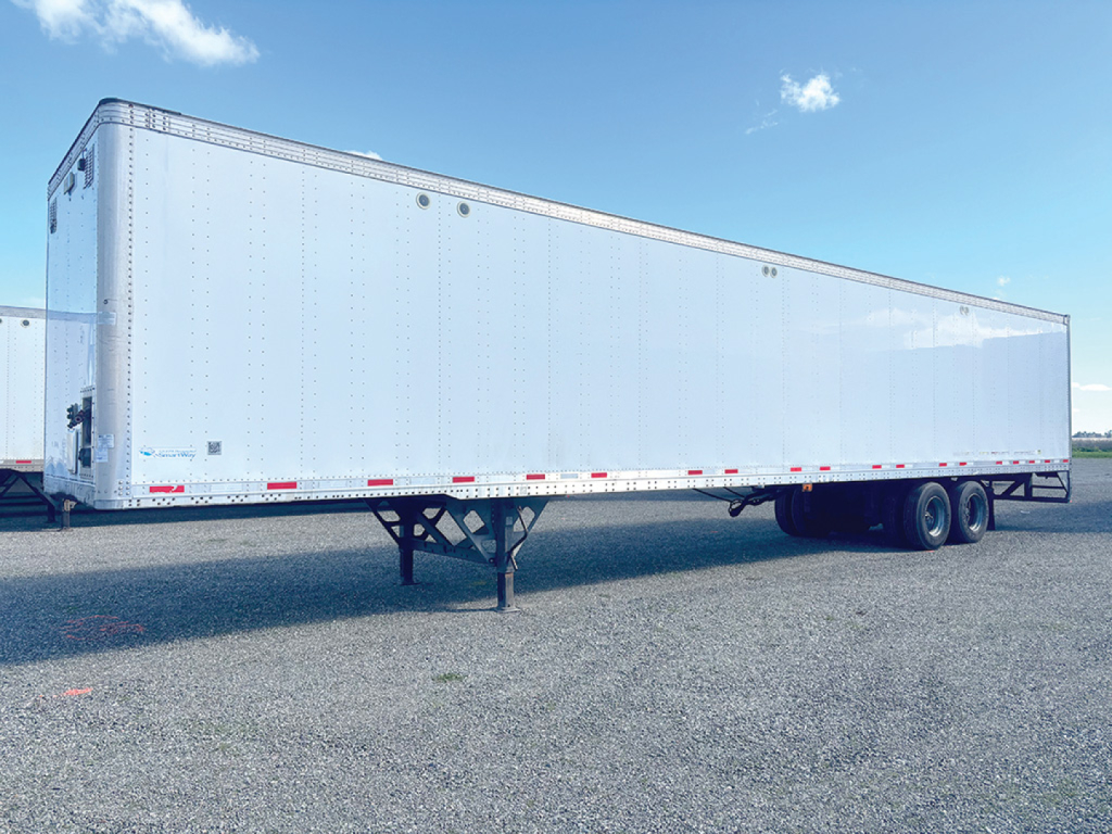 Trailer side view showing a white aluminum Vanguard trailer with dual rear wheels and landing gear, no visible branding text.