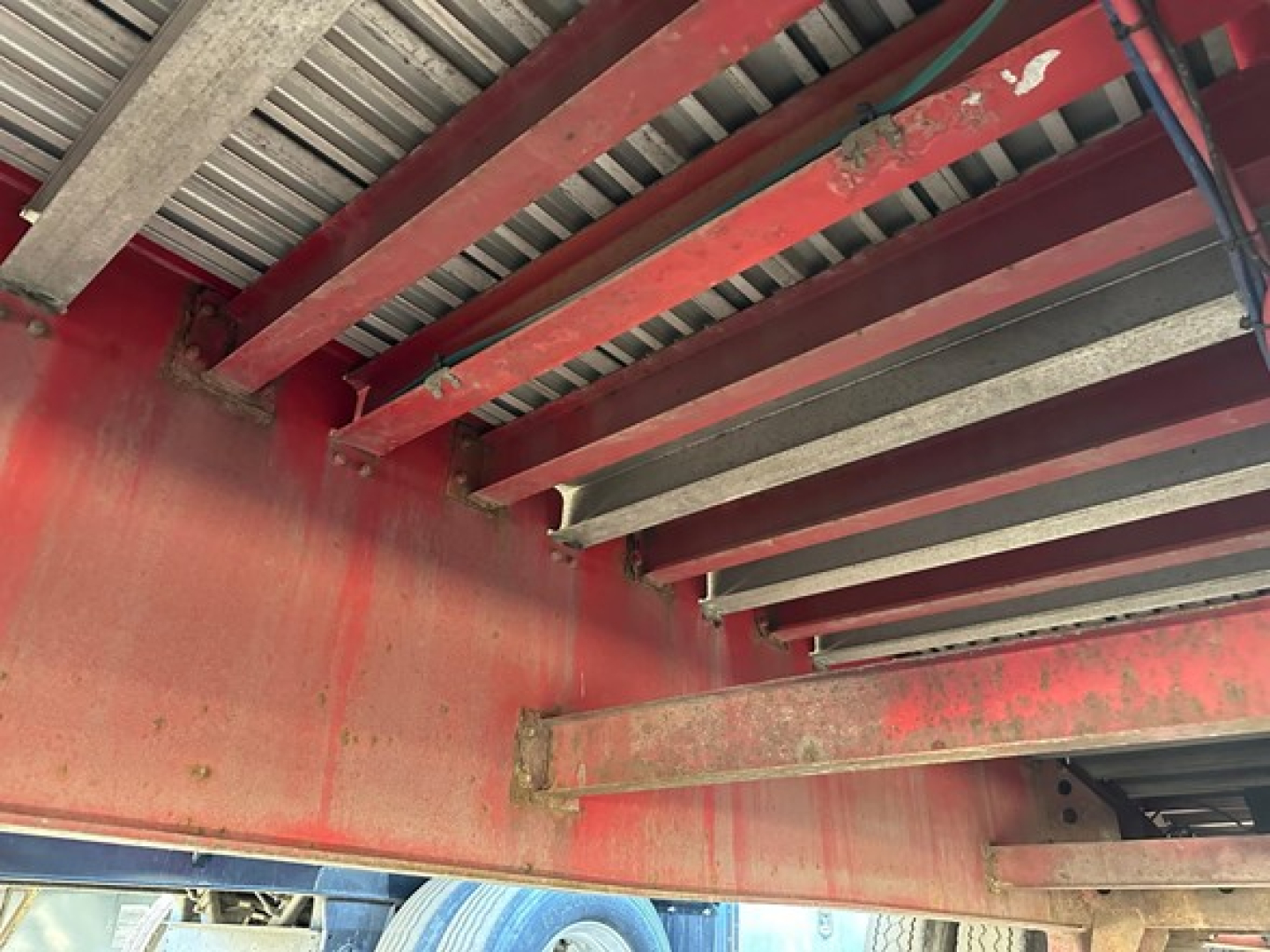Metal red Great Dane spread air combo flatbed trailer undercarriage framing with riveted rails and overhead beams.