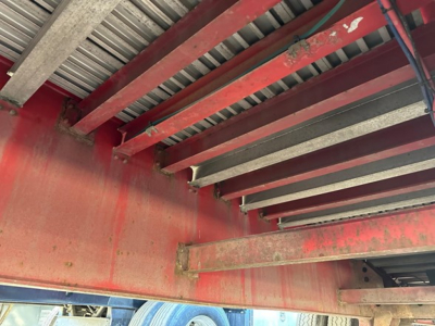 Metal red Great Dane spread air combo flatbed trailer undercarriage framing with riveted rails and overhead beams.