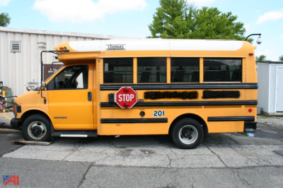 School bus in profile with STOP sign extended on the side and number 201, yellow body and black stripe, GMC Savana style bus.