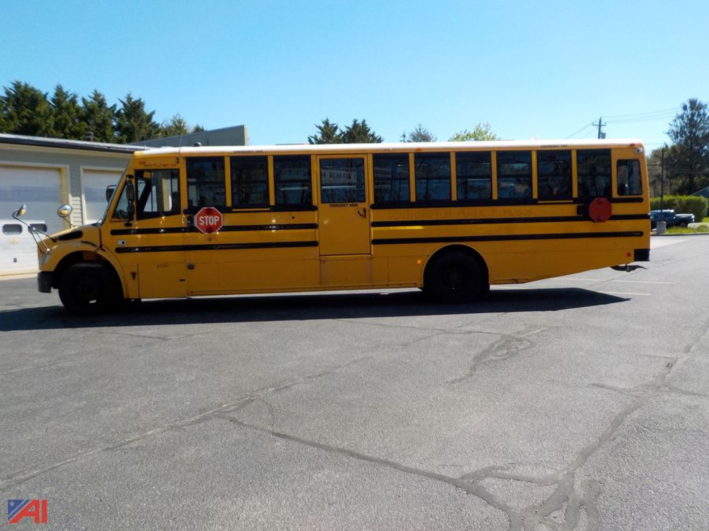 Yellow Freightliner Thomas school bus side view with stop sign, black stripes, and windows.