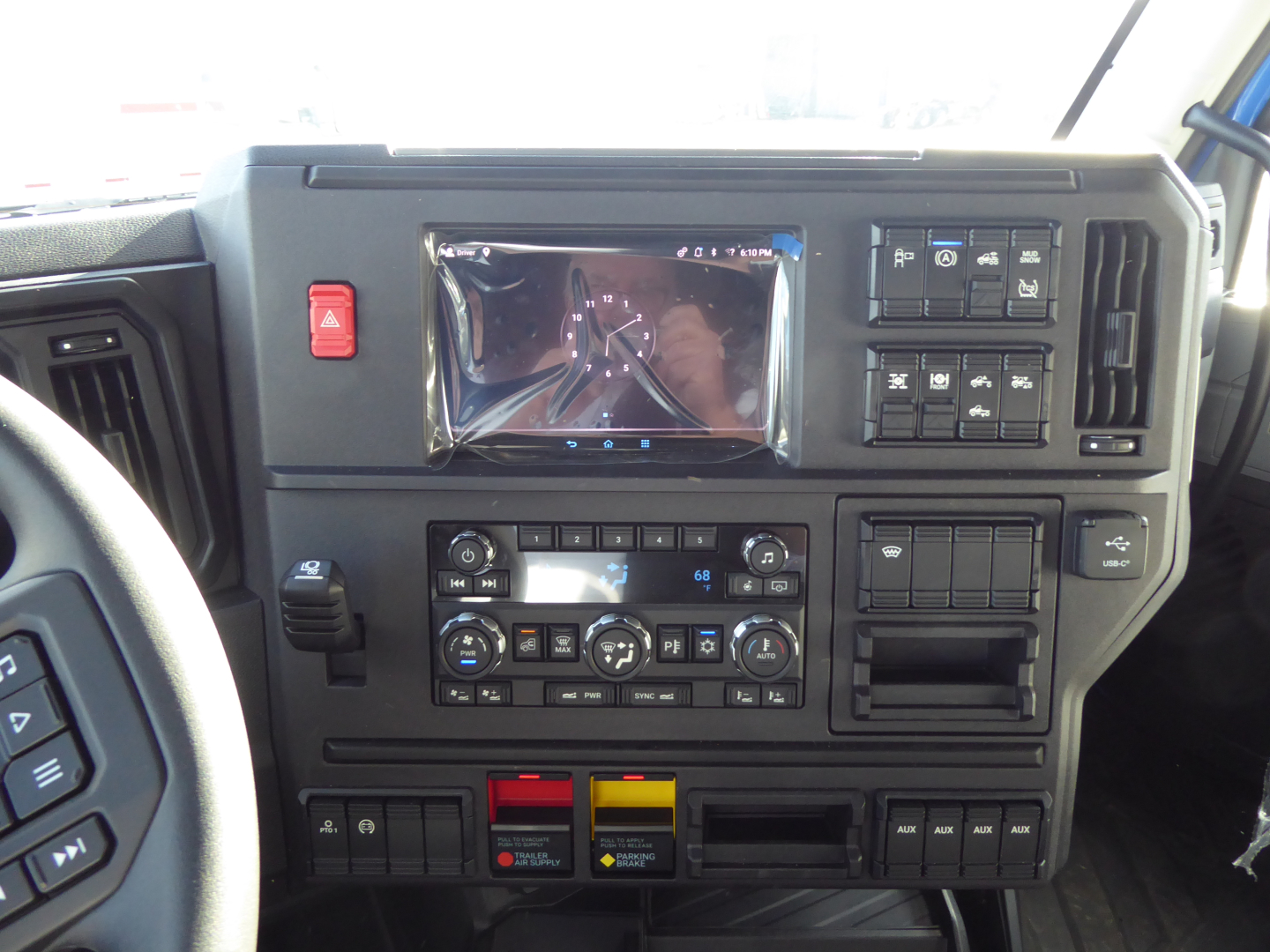 Dashboard view of a Mack PR64T64 truck cab showing instrument cluster, multimedia touchscreen, climate controls, and switches.