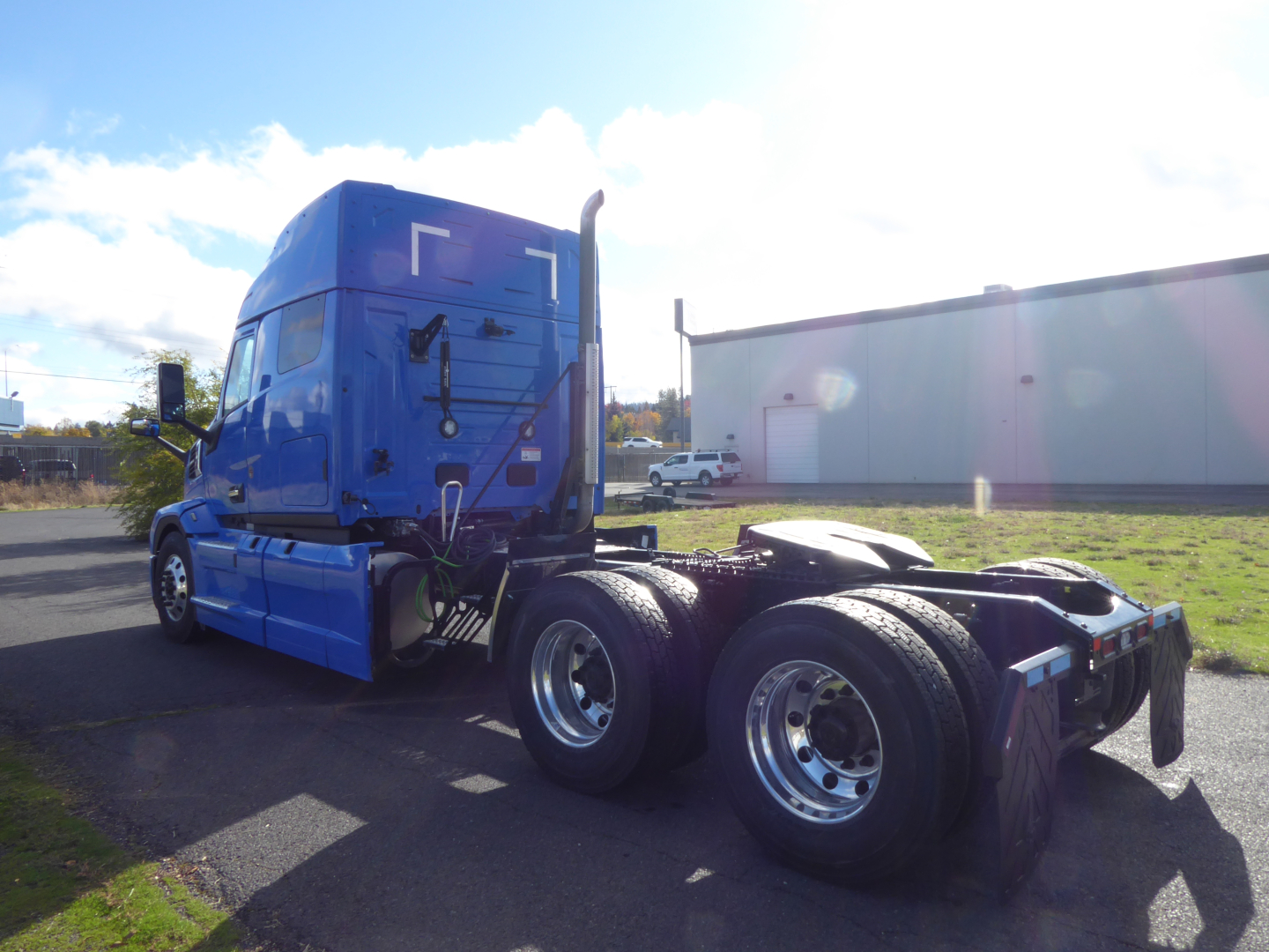 Mack PR64T64 conventional sleeper tractor in blue, rear view showing dual rear axles and fifth wheel; logo and vent detail on cab side.
