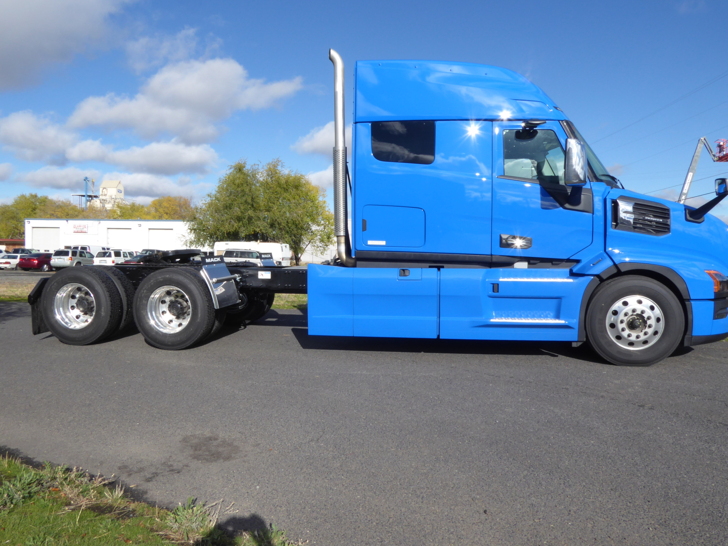 Truck side profile showing a blue Mack PR64T64 tractor cab and rear dual-axle chassis with fuel tanks and steps.