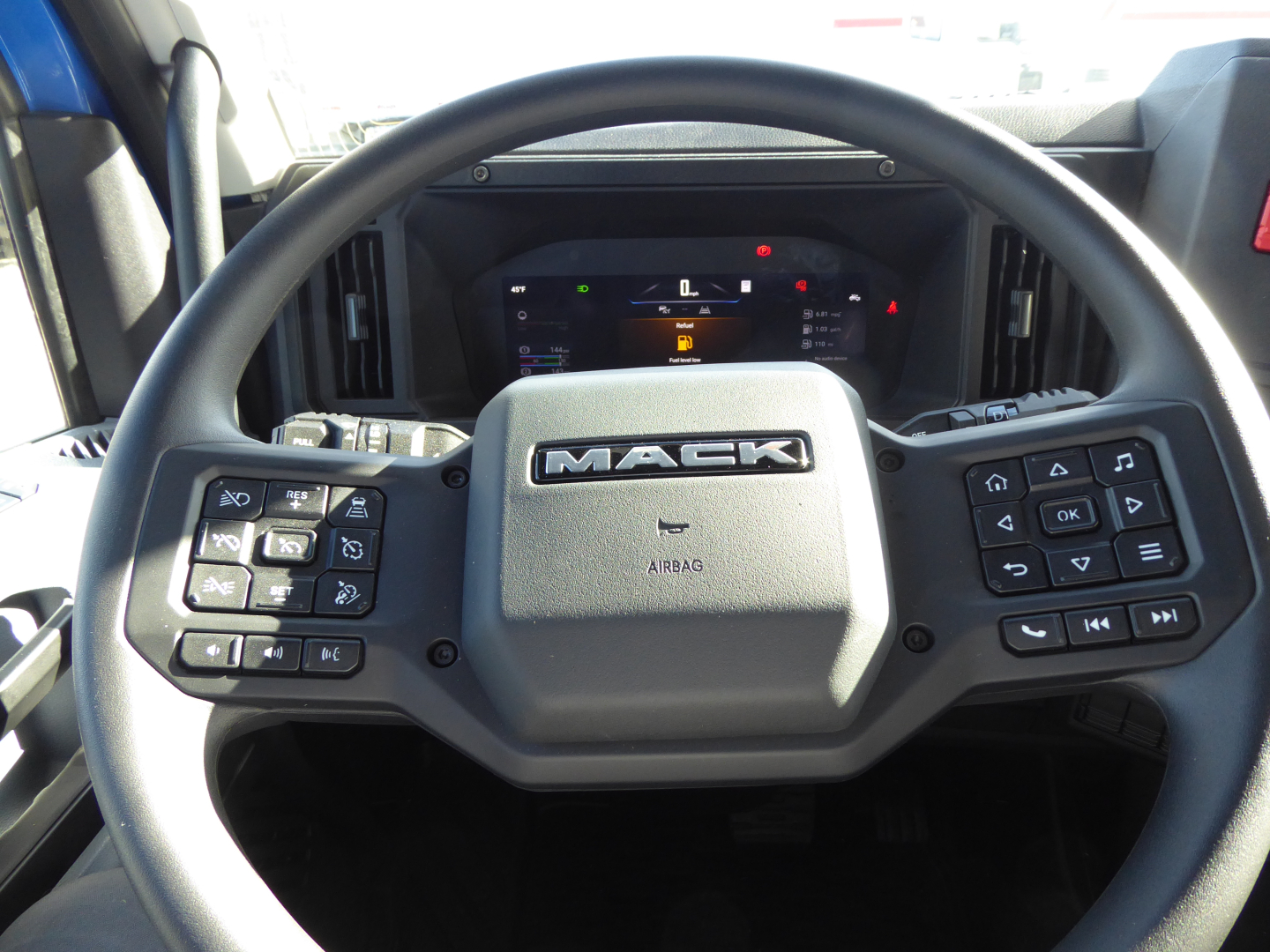 Mack PR64T64 truck steering wheel and dashboard view with Mack logo and control buttons visible.