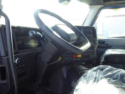Truck cabin interior: steering wheel, dashboard, and controls visible; plastic-covered seat. No visible labels or text readable besides general dashboard features.