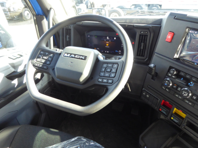 Mack PR64T64 truck cabin interior showing steering wheel with Mack logo and dashboard controls and digital display.