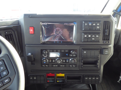 Dashboard view of a Mack PR64T64 truck cab showing instrument cluster, multimedia touchscreen, climate controls, and switches.
