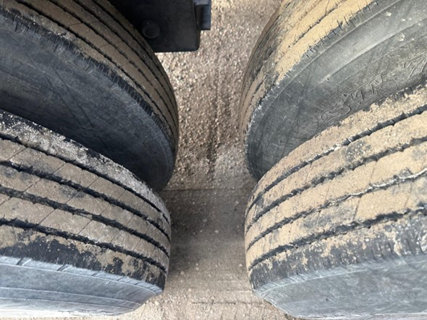 Two rear dual trailer tires with dirt and wear on treads and sidewalls, viewed from above.