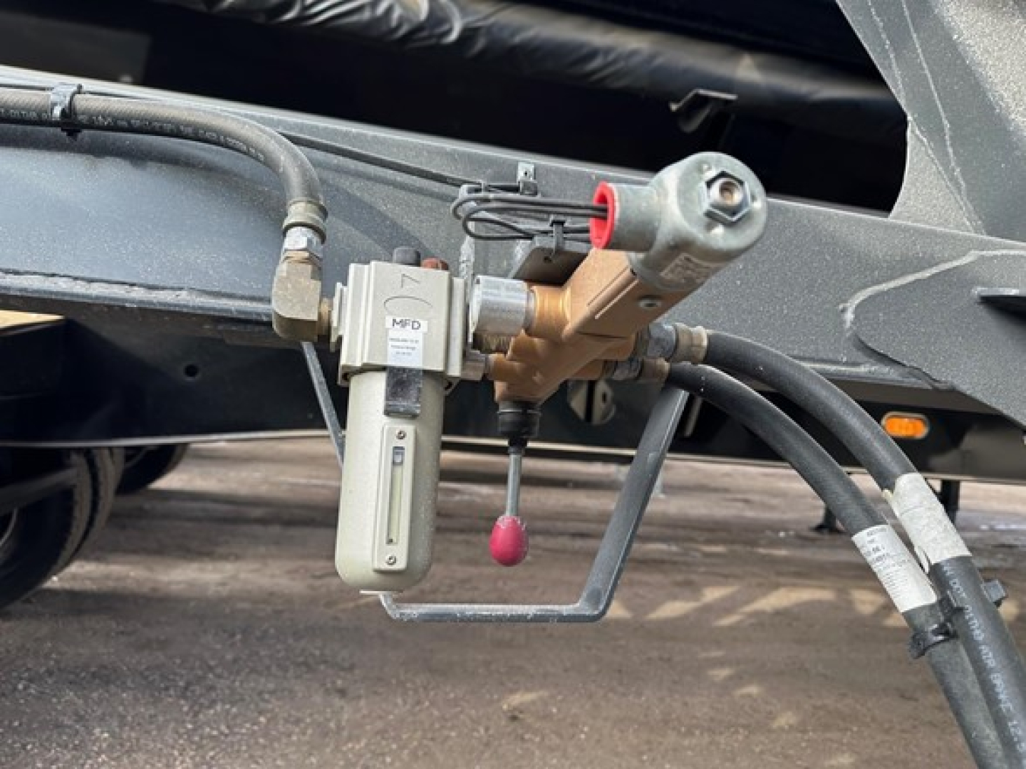 Bottom-dump trailer undercarriage featuring hydraulic valve, hose fittings, and control valve assembly.