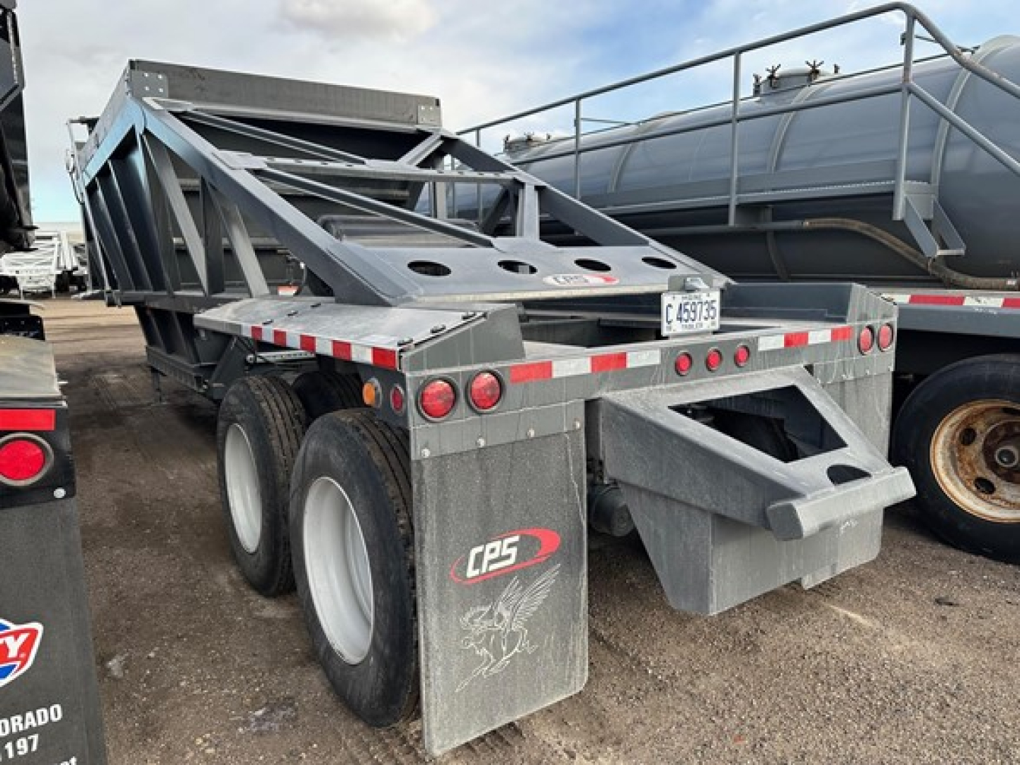 Trailer rear view of CPS 40' air ride bottom dump showing dual rear axles, mud flaps, metal frame, and tailgate area.