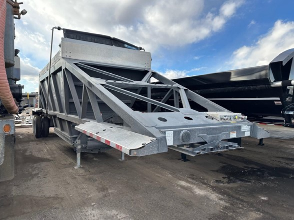 Trailer: 40' air ride bottom dump, metal truss frame, front hopper, dual-axle support, gray finish, visible hitch/tow assembly and side steps. Stock photo shows CPS 2025 model features.