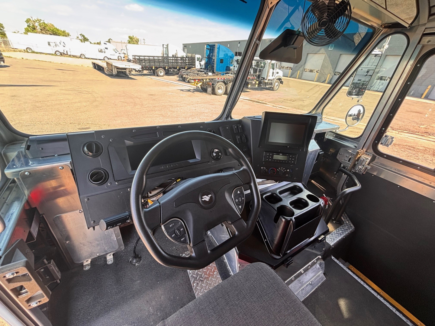 Interior cab of a 2025 Harbinger S534 step van showing steering wheel, dashboard, central console with cup holders, display screen, and various controls.