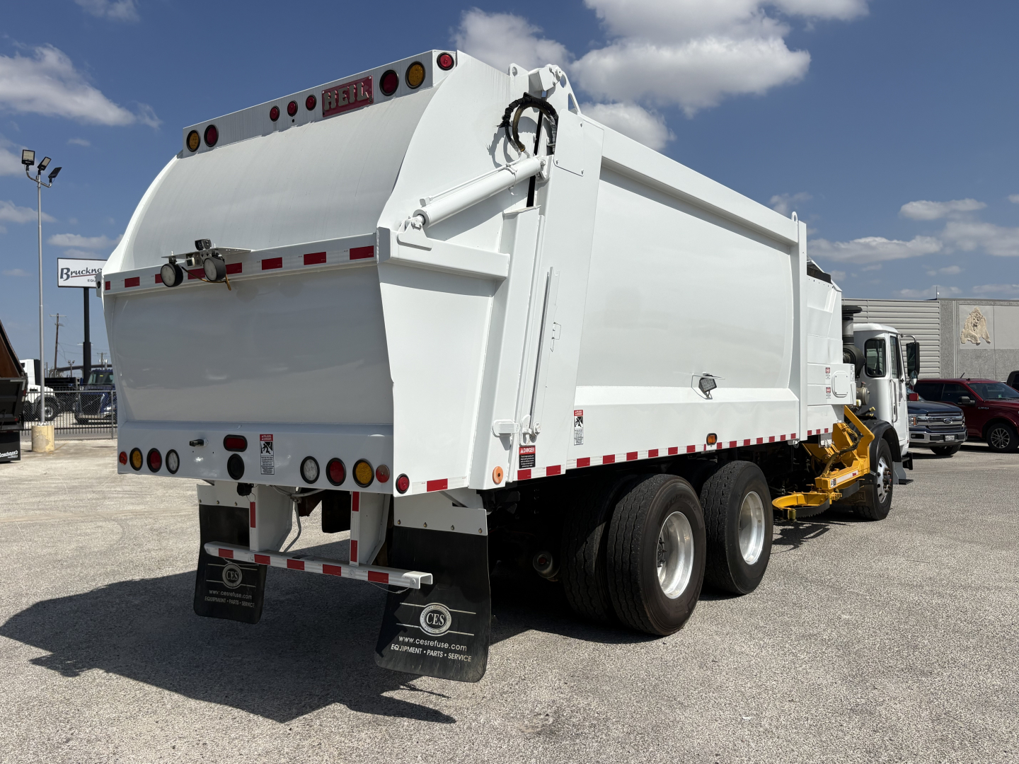 Rear view of 2019 Autocar XPEDITOR dump truck showing dump body and dual rear wheels with white body and yellow attachment.