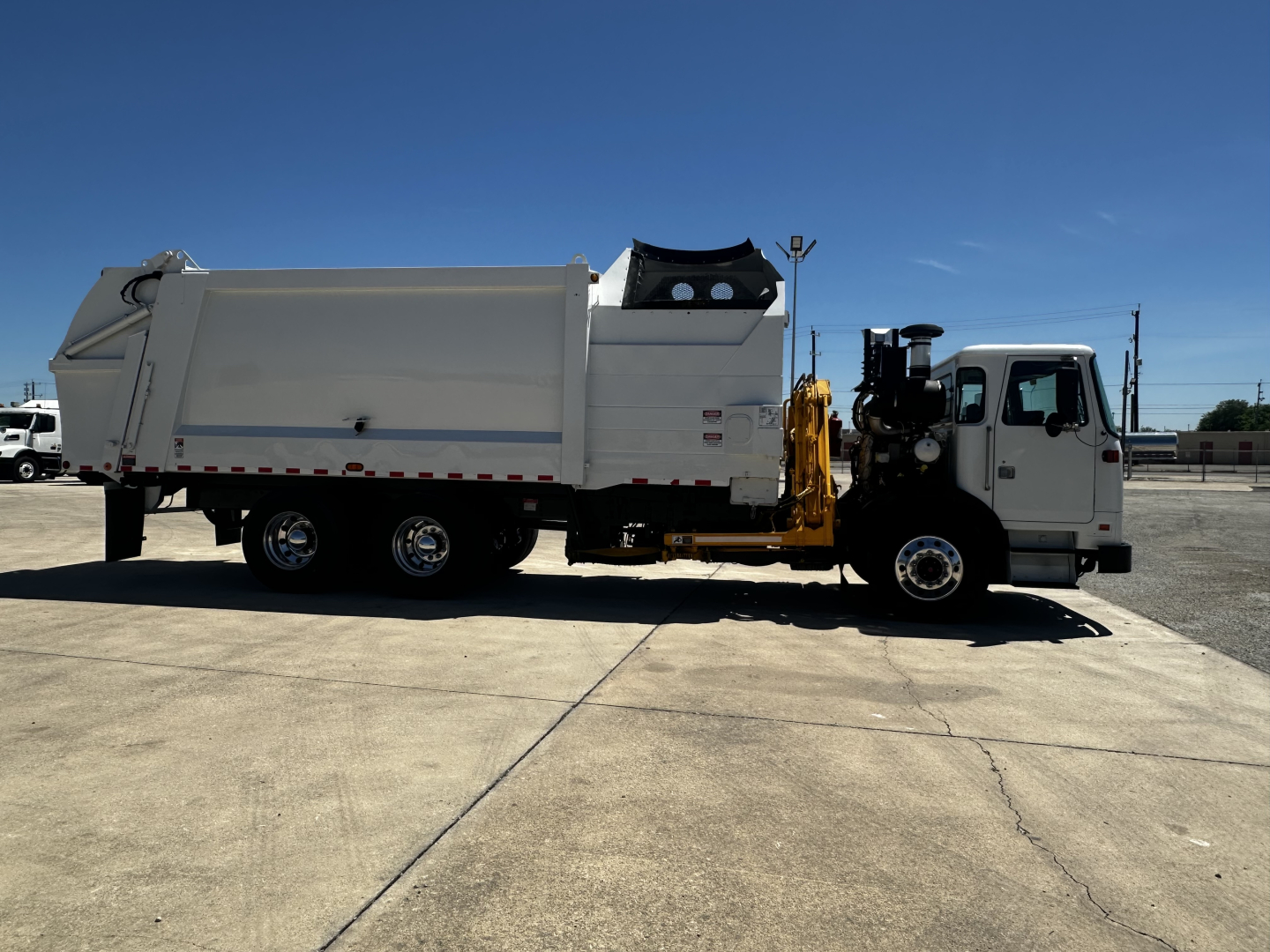 2019 Autocar XPEDITOR garbage truck side view showing large white body and cab, with hydraulic dump mechanism and rear dumping bed.