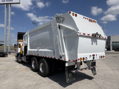 Garbage truck rear and side view showing dump body and rear lights.