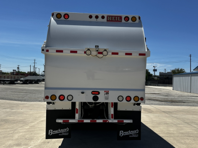 Rear view of a white Autocar XPEDITOR dump truck showing He included lights and rear bumper with Buckernee branding. visible text includes HEIL on top rear and a small label at center, with taillights and reflectors.