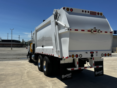 Autocar XPEDITOR dump truck rear three-quarter view showing Heit truck headboard, rear lights, and Bracken’s mudflaps; visible text includes HEIL on the rear, Bracken’s Mud Flaps, and identification plate areas.