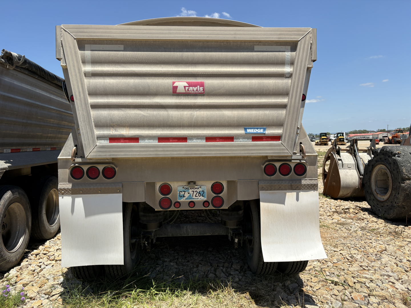 Dump trailer rear showing Travis logo, taillights,Mud flaps and license plate.