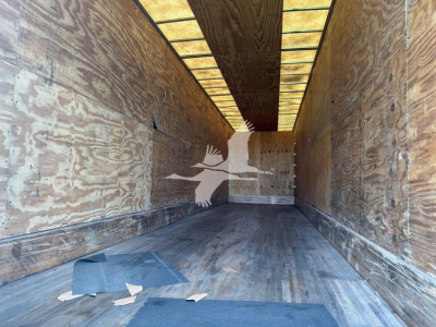 Manac drop van trailer interior showing wooden walls and floor with overhead interior lights.