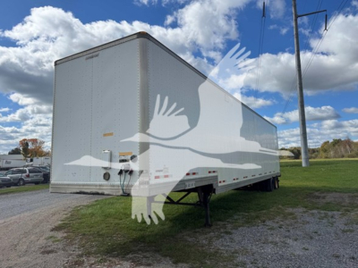 Manac sheet and post trailer in a lot, side and rear view showing exterior white aluminum cargo trailer with landing gear visible.