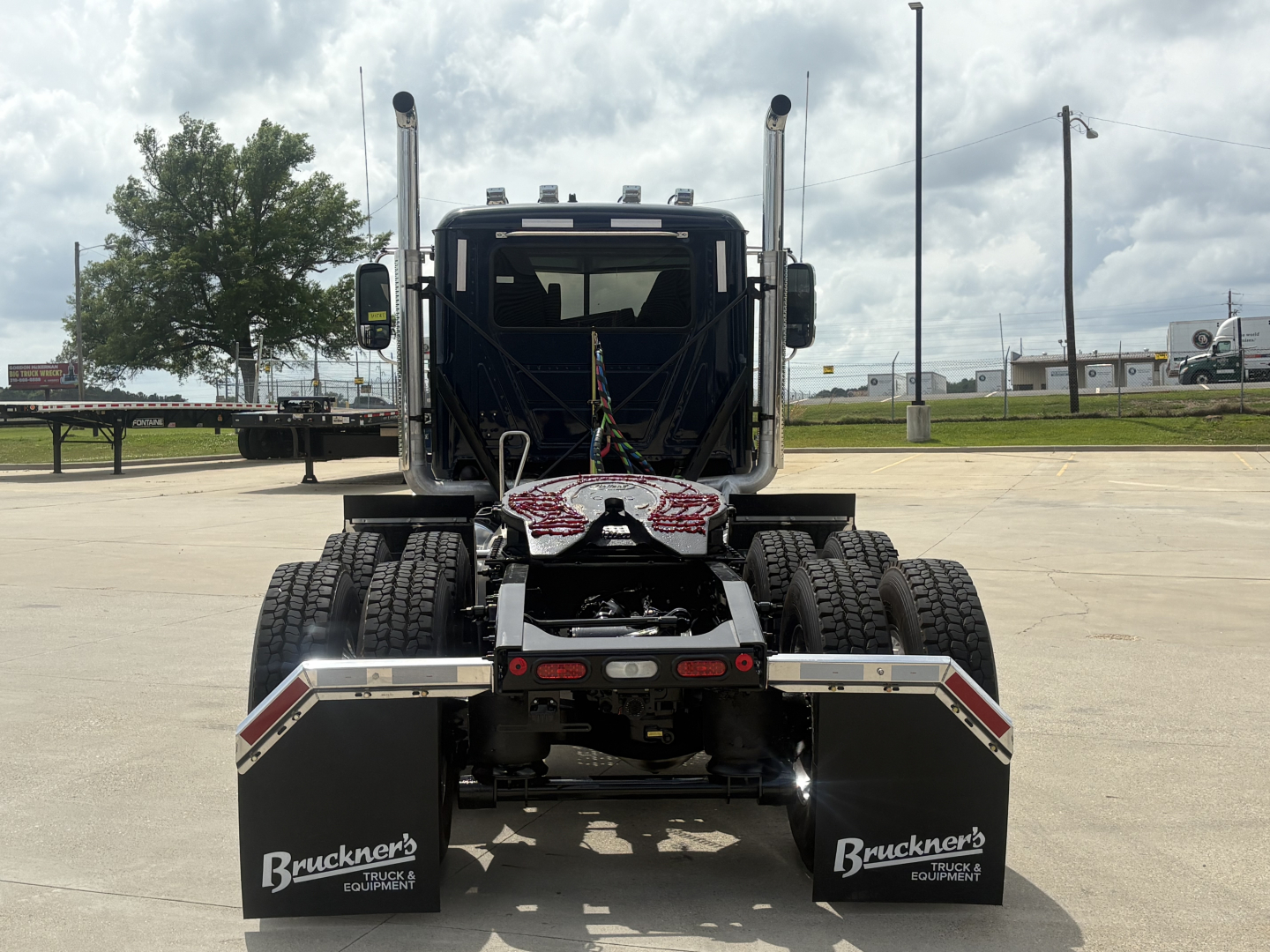 Rear view of a new 2027 Mack PI64T conventional daycab tractor showing dual rear axles and mud flaps with Bruckner's Truck & Equipment branding.