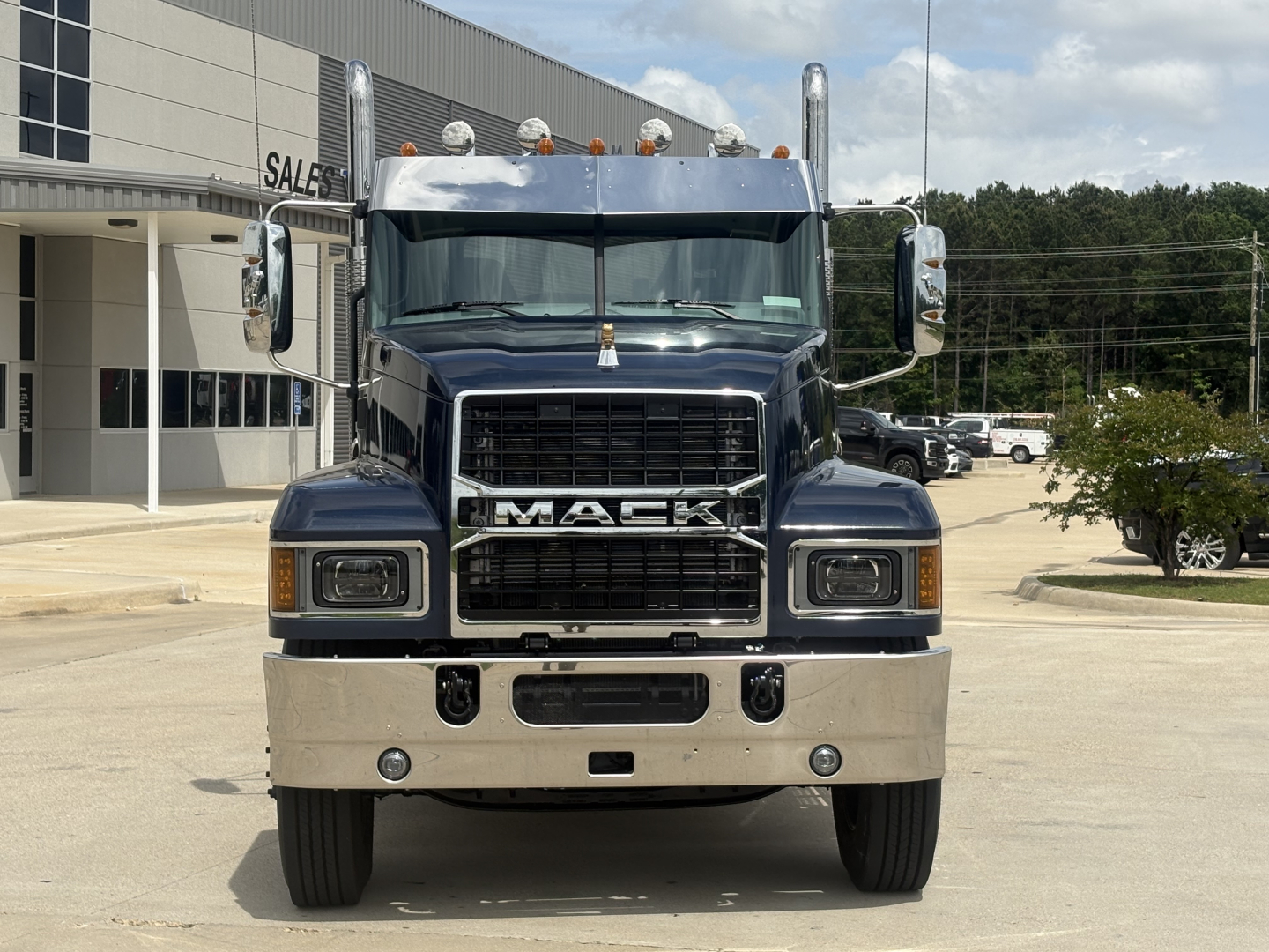 Front view of a new 2027 Mack PI64T conventional daycab tractor showing chrome grille, bumper, large mirrors, and cab details.