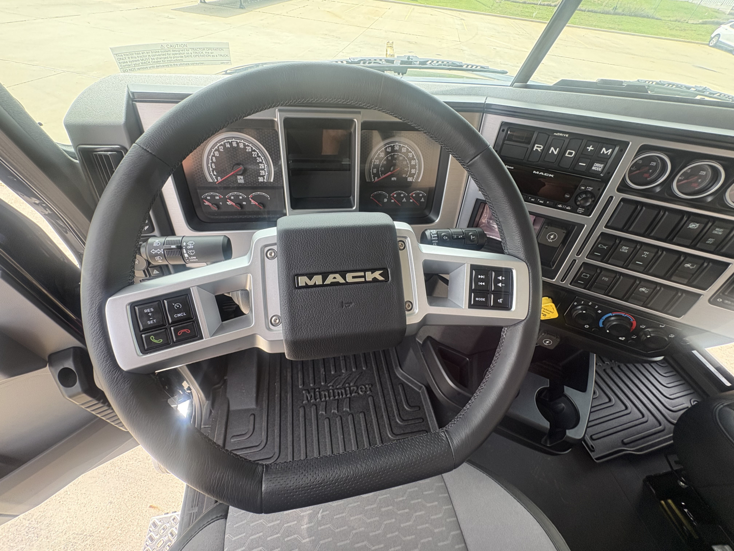 Mack PI64T truck interior showing steering wheel with Mack logo, instrument cluster, and control panels on the dashboard.