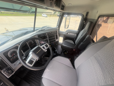 New Mack PI64T truck cabin interior showing steering wheel, dashboard gauges, and front seats.